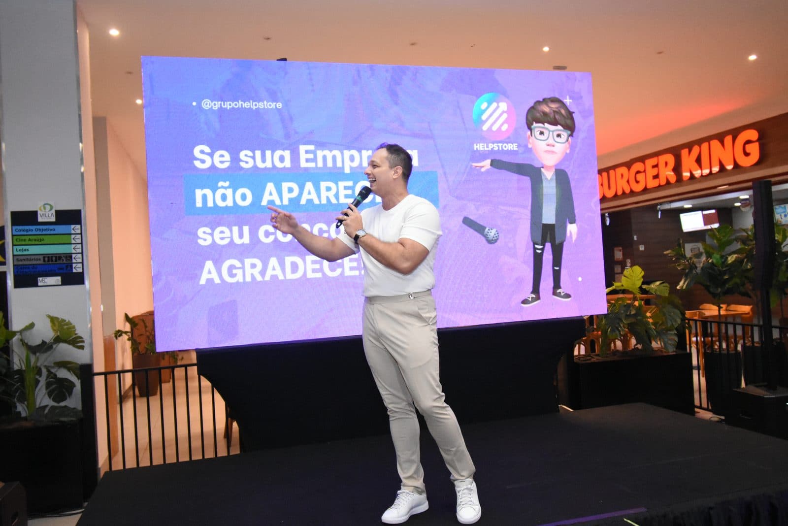 Palestrante no palco diante do slide “Se sua empresa não aparece, seu concorrente agradece”