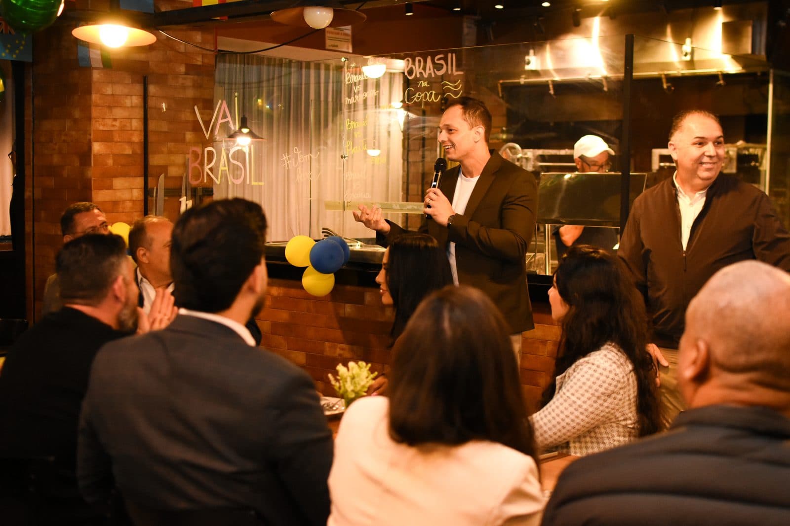 Palestrante com microfone falando para empresários em restaurante