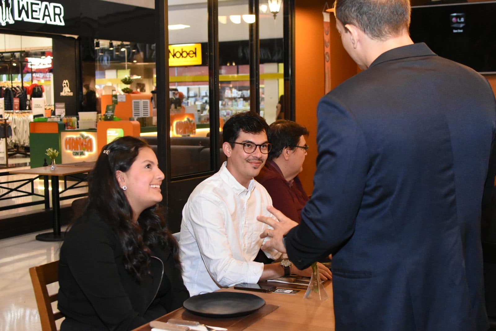 Cumprimento entre participantes à mesa