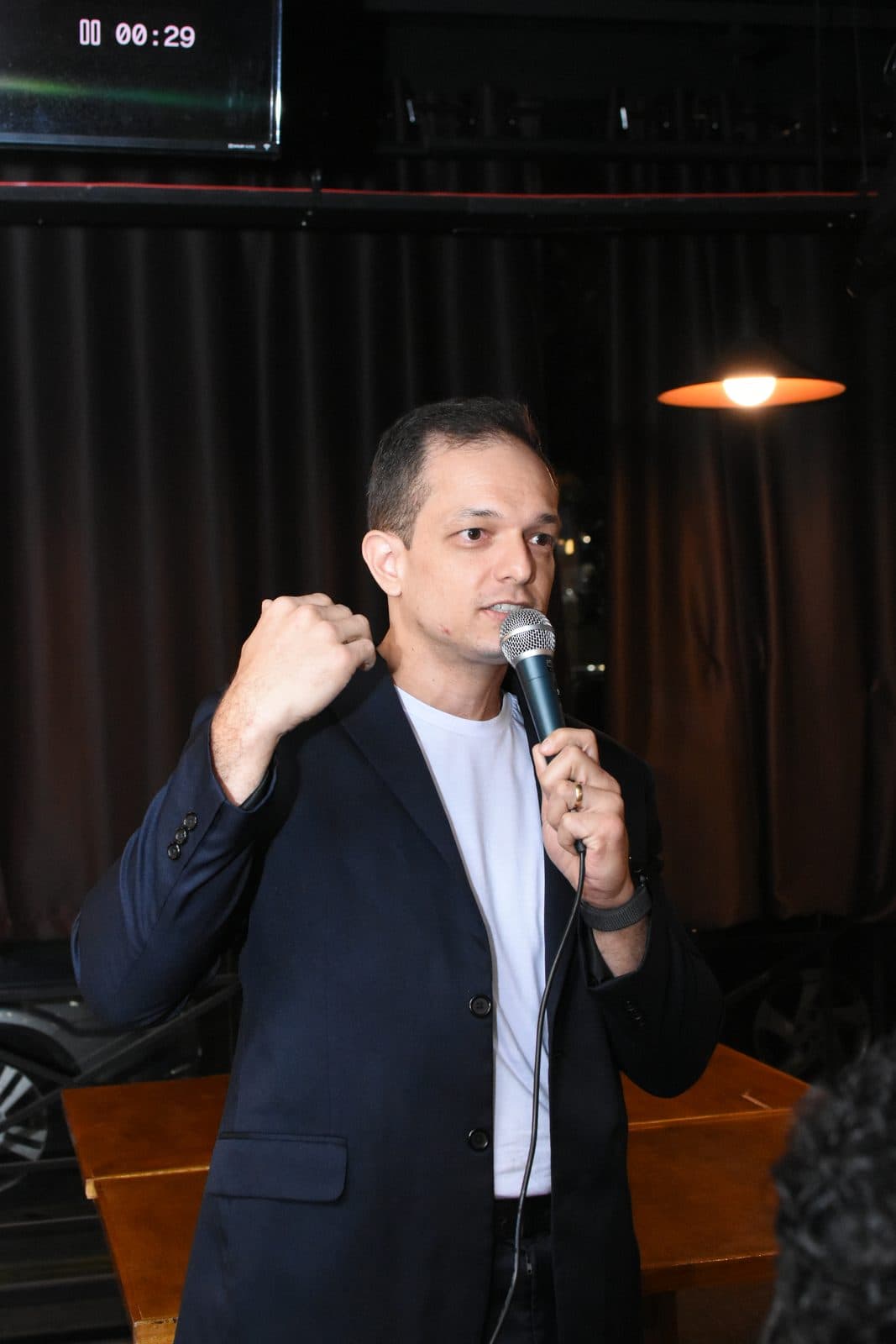 Palestrante gesticulando enquanto fala ao microfone