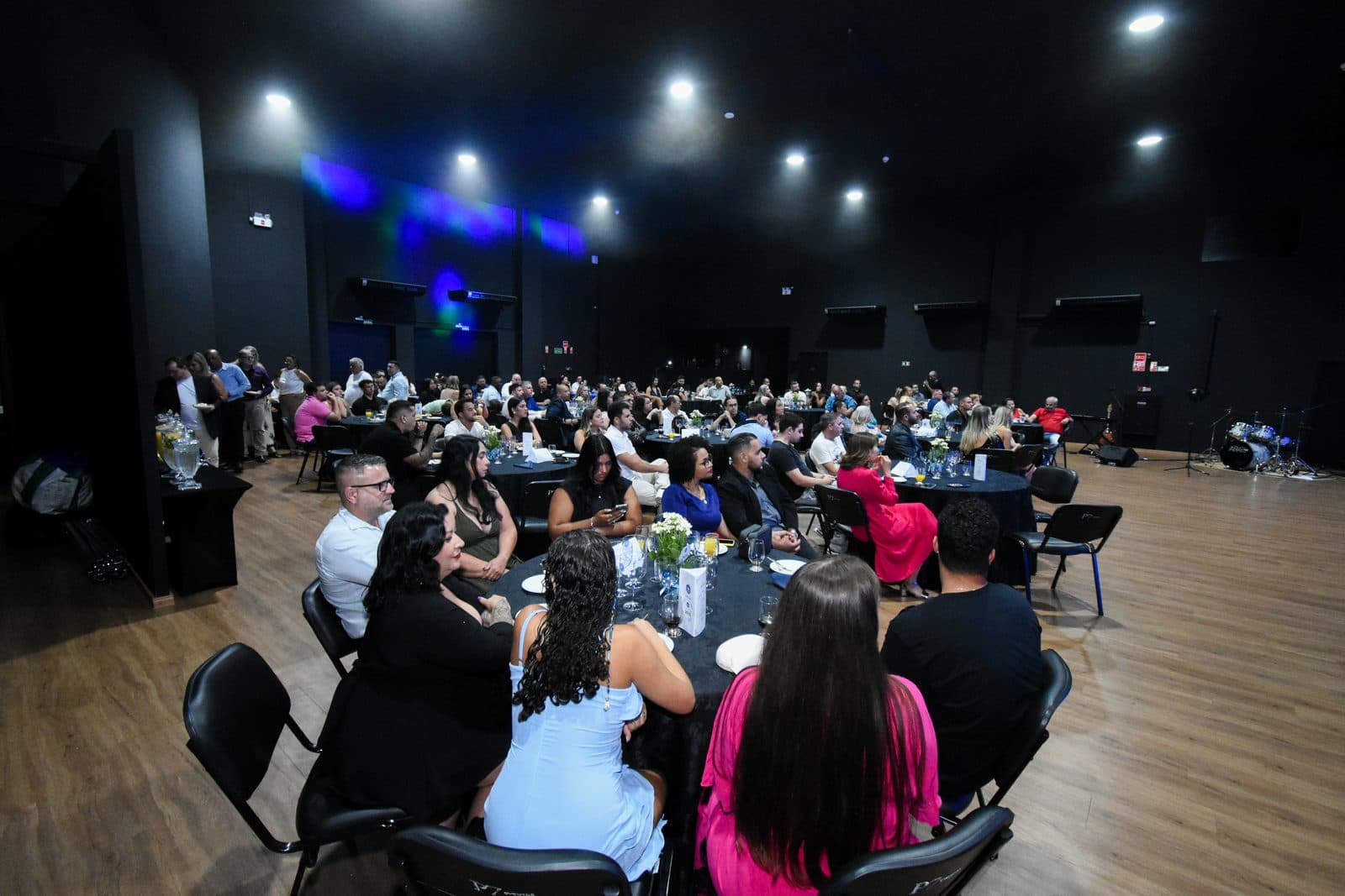Salão de eventos com mesas e público reunido